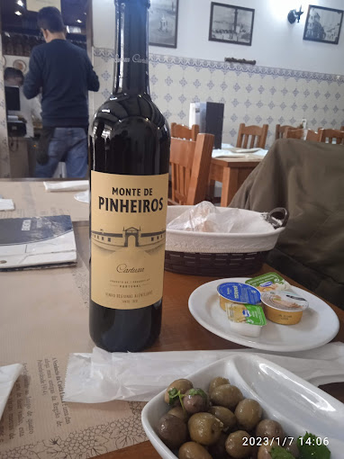 Mesa posta com couvert, azeitonas e garrafa de vinho tinto alentejano no Restaurante A Toca